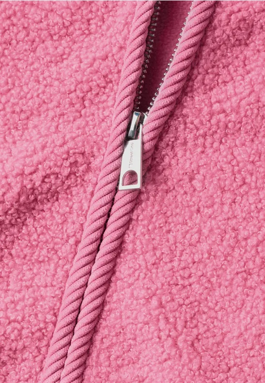 Nahaufnahme eines rosa Reißverschlusses auf flauschigem Teddy-Fleece-Stoff.