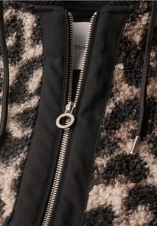 Nahaufnahme einer flauschigen Jacke mit Animal-Print und mittigem Reißverschluss mit Ringschieber