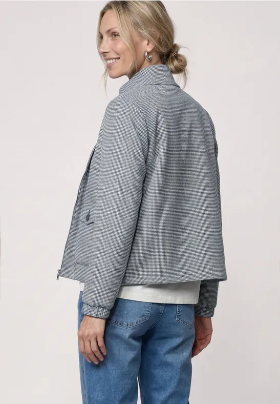 Vue de dos d'une personne en veste grise, jean bleu et chignon décontracté.