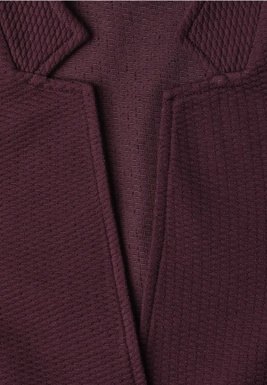 Nahaufnahme eines burgunderfarbenen Strickpullovers mit V-Ausschnitt und texturiertem Muster.