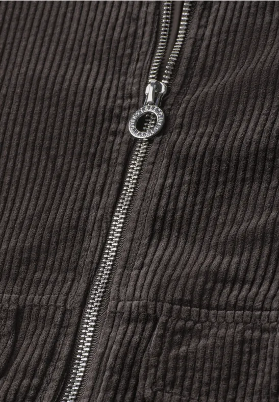 Nahaufnahme einer braunen Kordjacke mit Metallreißverschluss und rundem Zipperzug