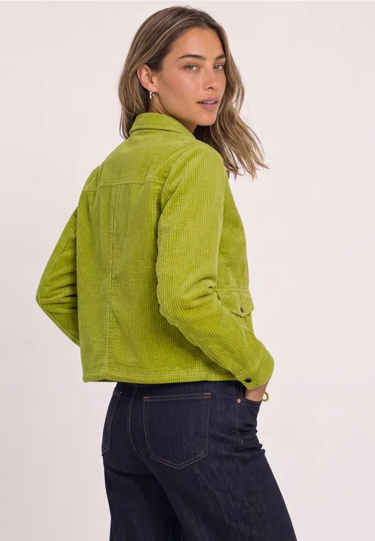 Frau im Profil mit grüner Jacke und dunkler Jeans.