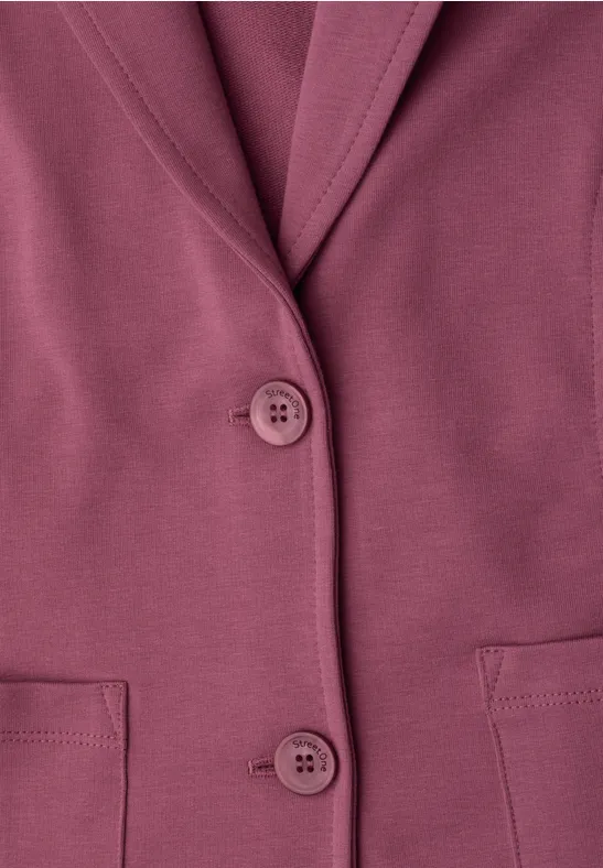 Nahaufnahme eines bordeauxfarbenen Blazers mit zwei Knöpfen und zwei Taschen.