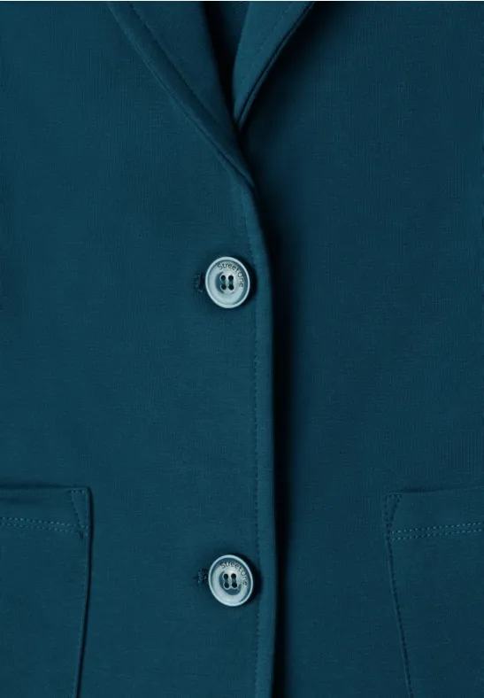 Nahaufnahme eines petrolfarbenen Blazers mit zwei Knöpfen und aufgesetzten Taschen.