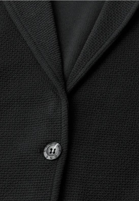 Schwarzer, fein strukturierter Blazer mit Reverskragen und einzelner Knopfleiste aus nächster Nähe.