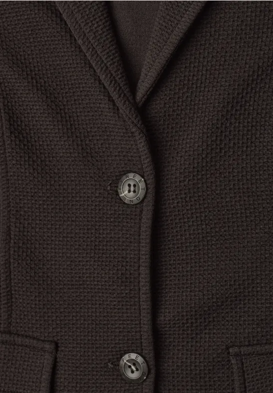 Gros plan d’un gilet marron en maille avec deux boutons et poches avant.