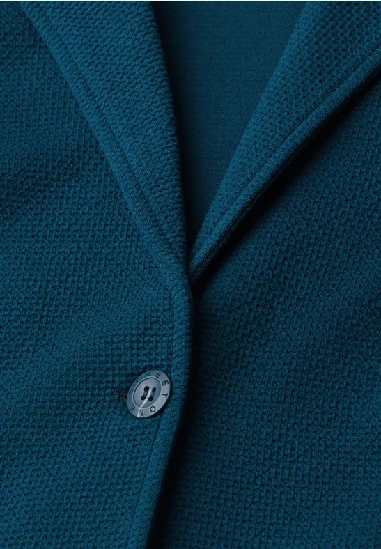 Nahaufnahme eines tealblauen Strickblazers mit Reverskragen und Knopf