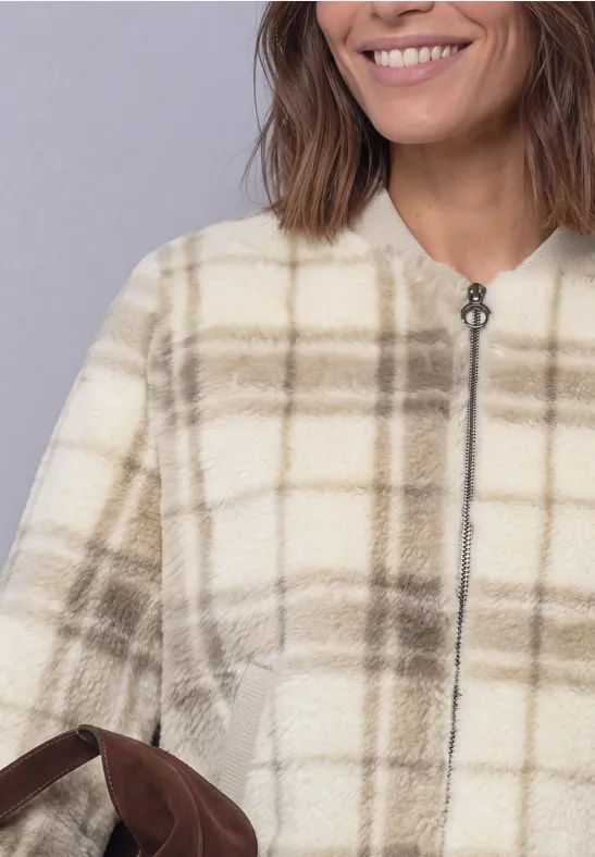 Veste pelucheuse à carreaux beige crème, fermeture éclair et poches latérales.