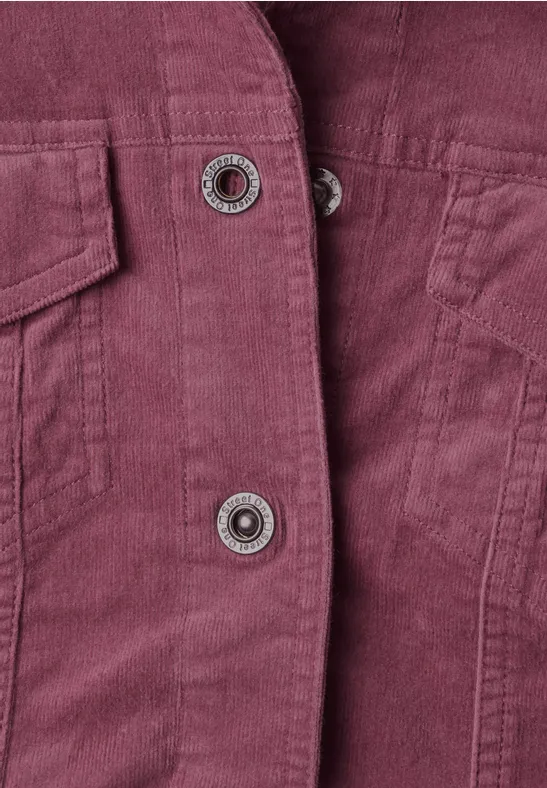 Detailaufnahme einer violettroten Cordjacke mit zwei Druckknöpfen und aufgesetzter Tasche.
