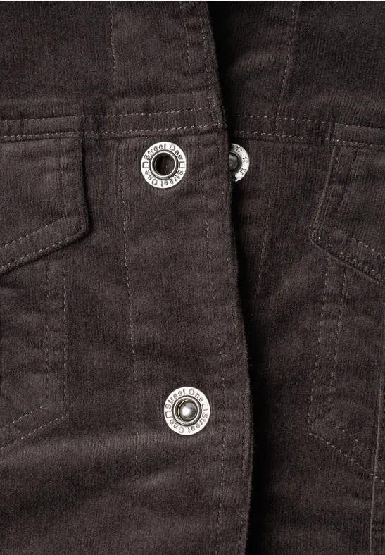 Gros plan sur un manteau en velours côtelé brun foncé avec des boutons-pression argentés.