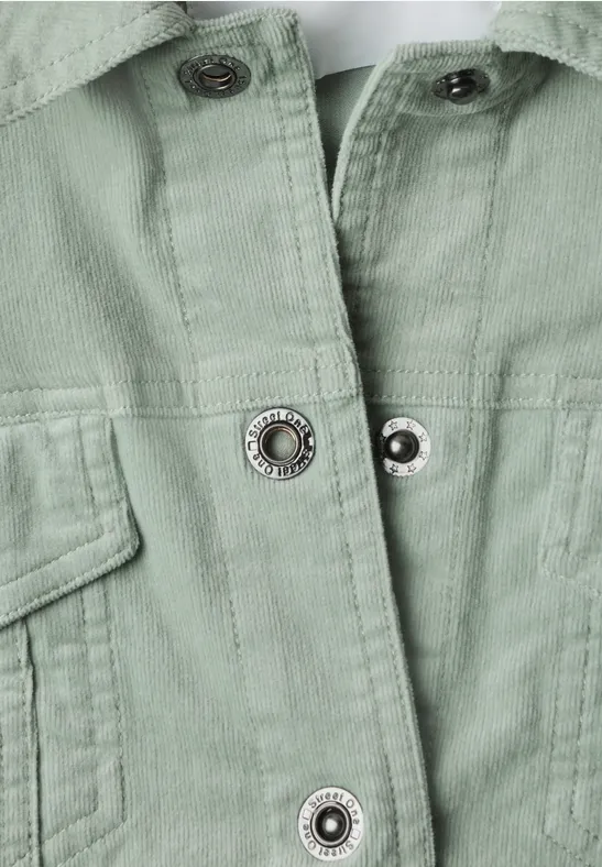 Gros plan d'une veste vert pâle avec boutons-pression et poches plaquées.