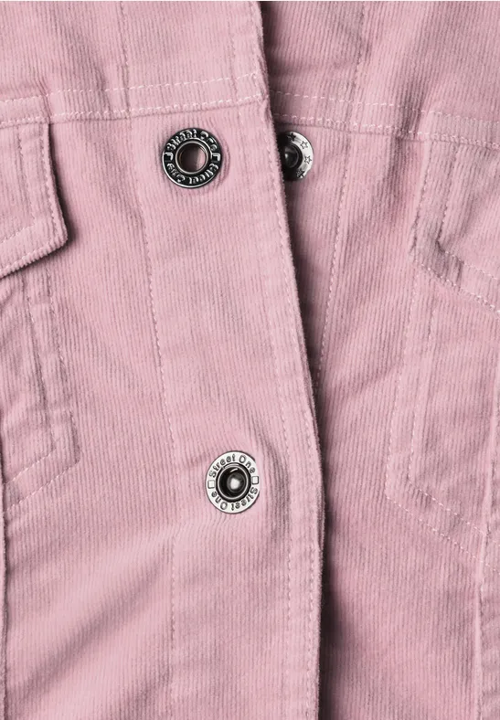Gros plan d’une veste en velours côtelé rose avec boutons-pression métalliques.
