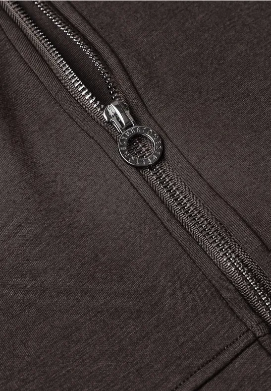 Close-up van een bruin kledingstuk met een zilverkleurige rits en ronde rits-trekker.