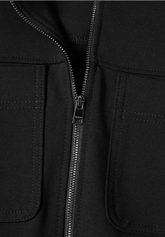 Nahaufnahme einer schwarzen Jacke mit durchgehendem Reißverschluss und aufgesetzten Taschen.