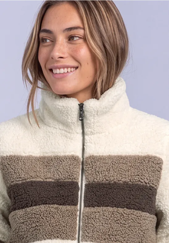 Frau lächelt und trägt eine gestreifte Fleecejacke in Cremeweiß und Braun.