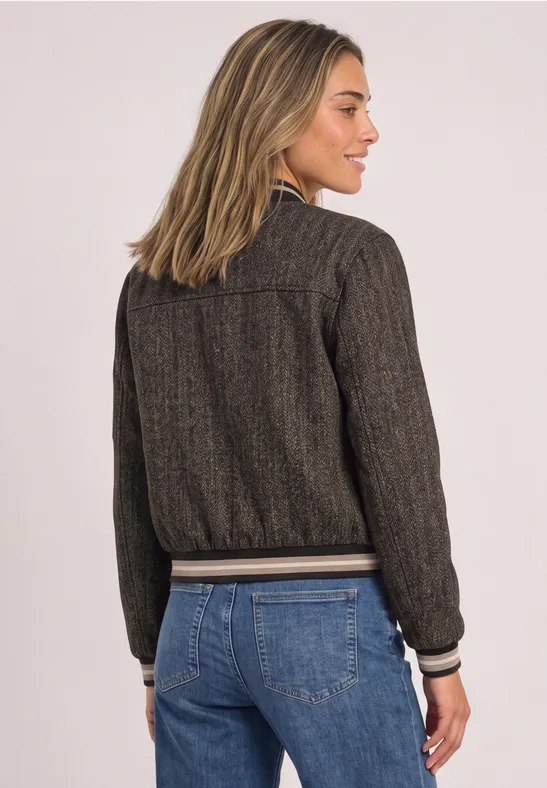 Femme de dos portant une veste bomber brune chinée à finitions côtelées et un jean bleu.