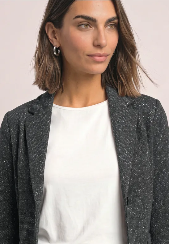 Porträt einer Frau mit braunen Haaren, schwarzem Blazer und weißem T-Shirt.