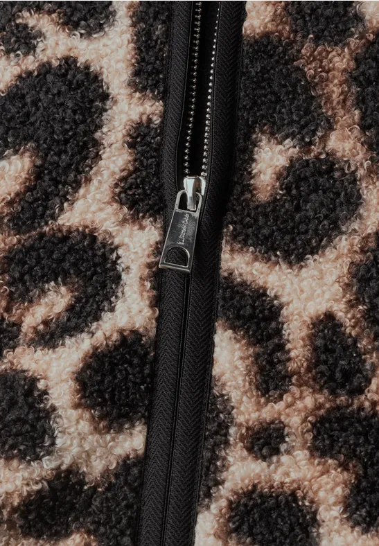 Nahaufnahme eines Leopardenmusters mit schwarzem Reißverschluss auf flauschigem Stoff.