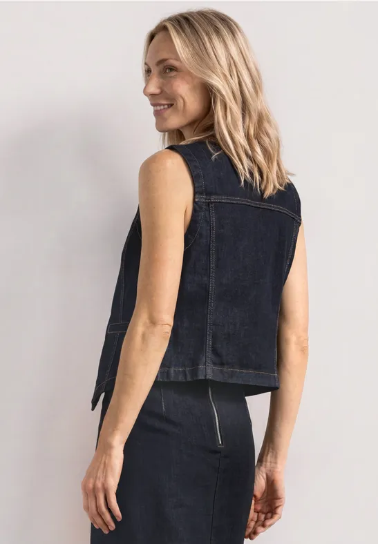 Achteraanzicht: persoon in mouwloze donkerblauwe denimvest en -rok met rits, neutrale achtergrond