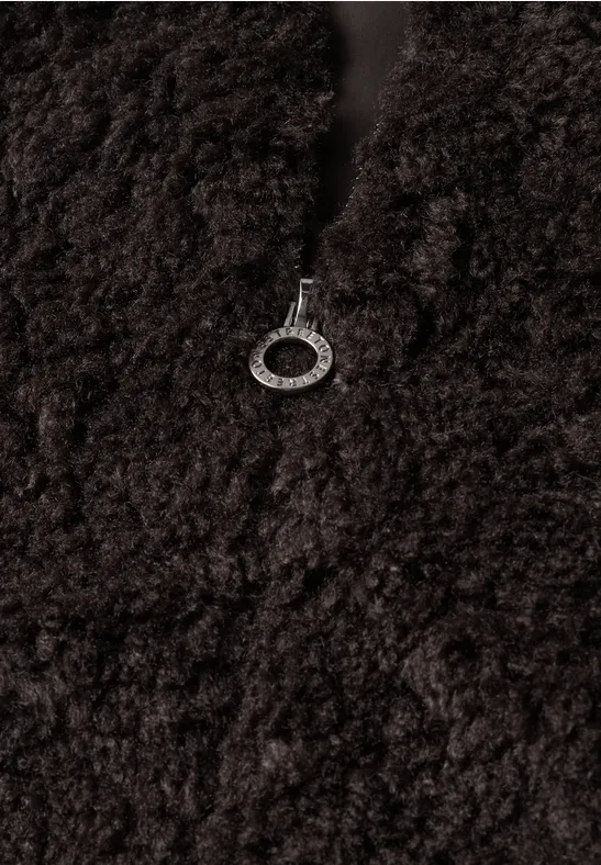 Nabijopname van donkerbruin teddyfleece met zilverkleurige ritstrekker.