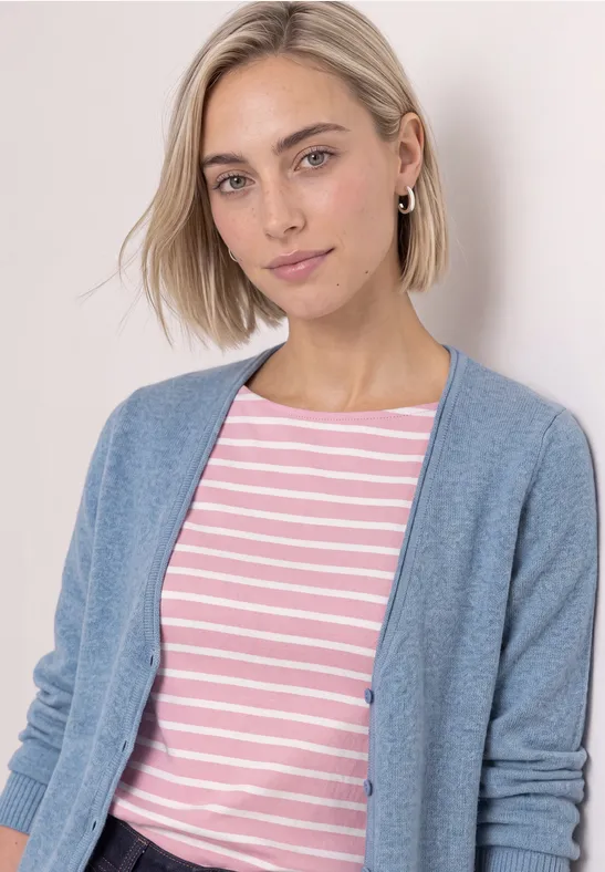 Junge Frau mit kurzem blondem Haar trägt rosa-weiß gestreiftes Shirt und hellblauen Cardigan.
