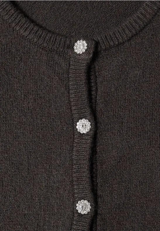 Nahaufnahme eines dunkelbraunen Strickcardigans mit drei silbernen, blumenförmigen Knöpfen.