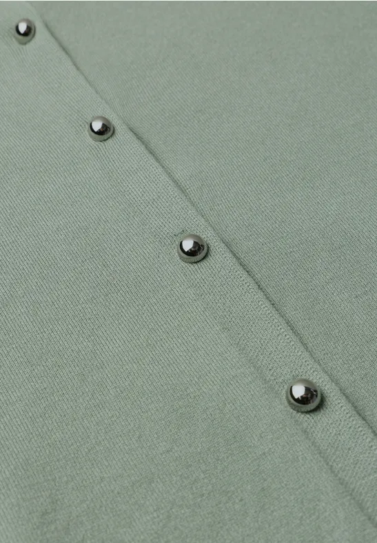 Nahaufnahme eines hellgrünen Strickcardigans mit Reihe glänzender Metallknöpfe.