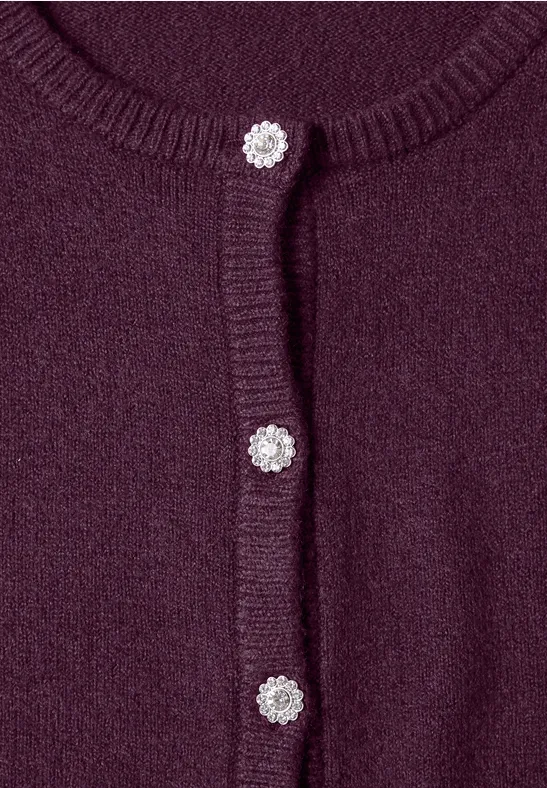 Nahaufnahme eines purpurfarbenen Strickcardigans mit funkelnden silbernen Knöpfen