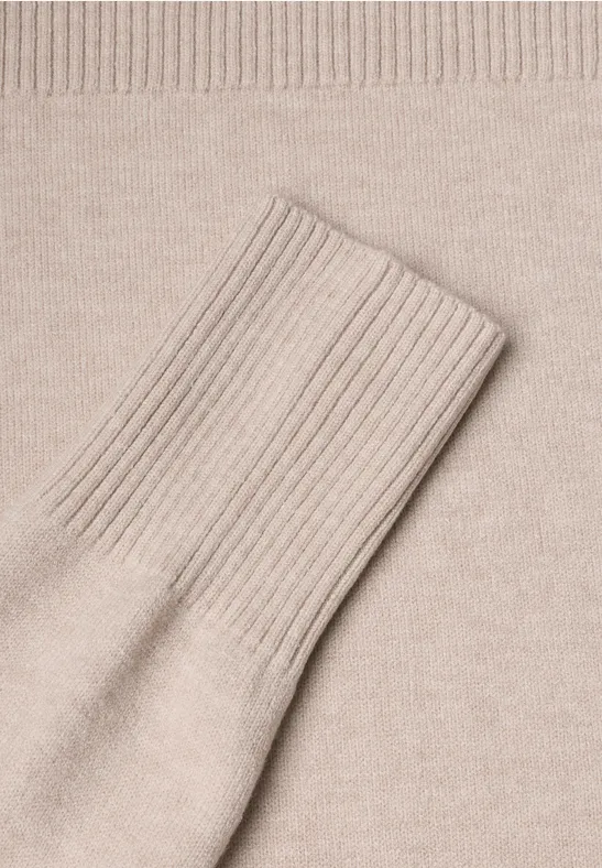 Gros plan sur un pull en maille beige avec manche étendue