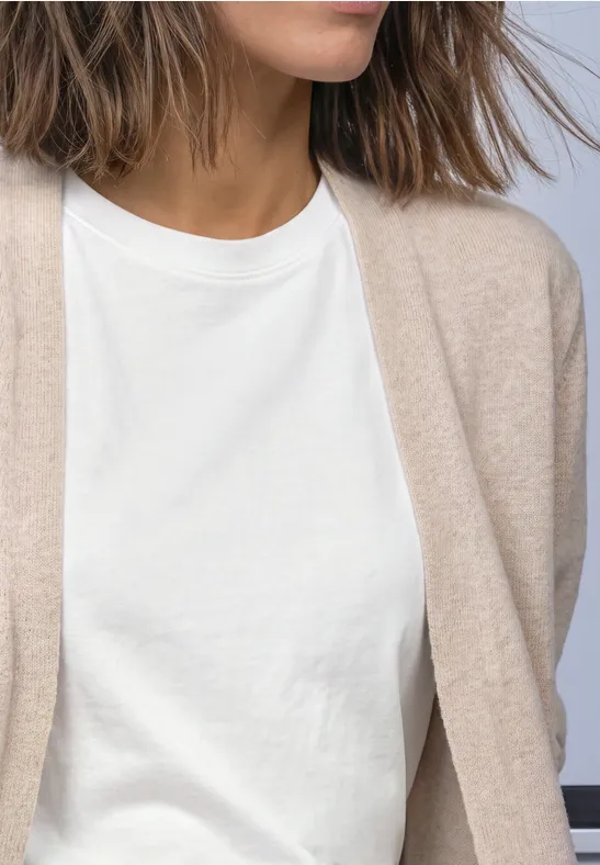 Gros plan d’une personne portant un t-shirt blanc et un gilet beige.
