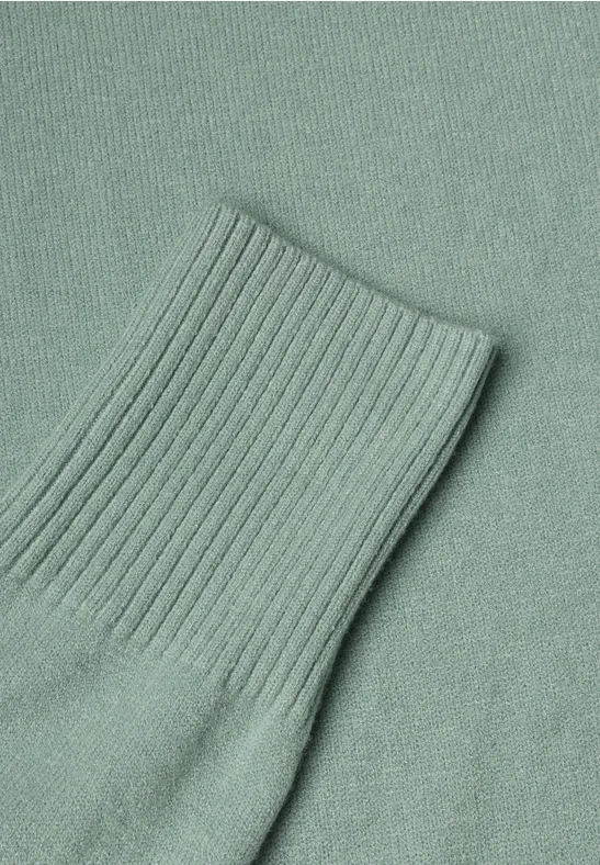 Ein mintgrüner Strickpullover mit geripptem Ärmelbündchen.