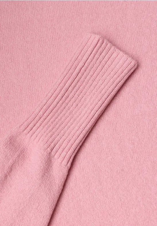 Nahaufnahme eines rosa Strickkleidungsstücks mit Rippbündchen.