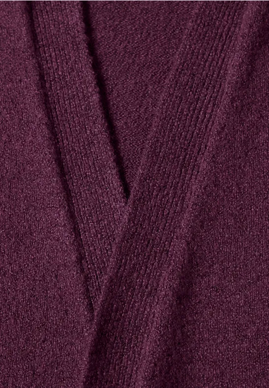 Nahaufnahme eines burgunderroten, gestrickten V-Ausschnitt-Pullovers mit feiner Maschenstruktur.