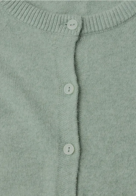 Nahaufnahme eines pastellgrünen Strickcardigans mit drei Knöpfen.