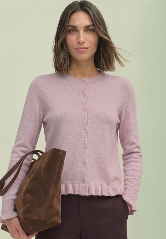 Frau in pastellrosa Strickjacke mit Volantsaum, lässige braune Umhängetasche.