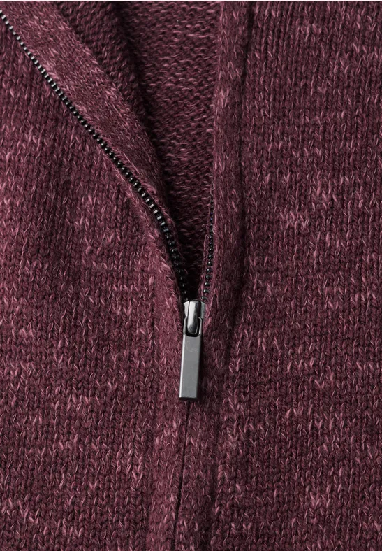 Nahaufnahme einer bordeauxroten Strickjacke mit silbernem Reißverschluss.