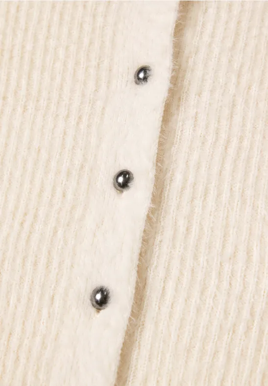 Beiges geripptes Strickstück mit drei schwarzen Knöpfen.