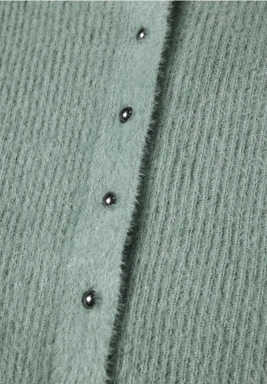 Flauschiger, salbeigrüner Strickstoff mit senkrechter Reihe silberner Druckknöpfe.
