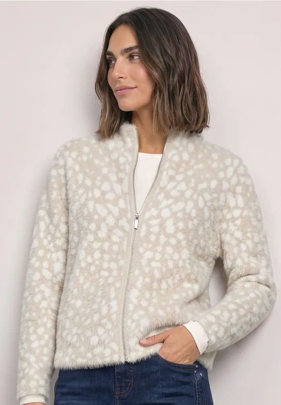 Frau in heller, flauschiger Jacke mit zartem Leopardenmuster und Reißverschluss vorne.
