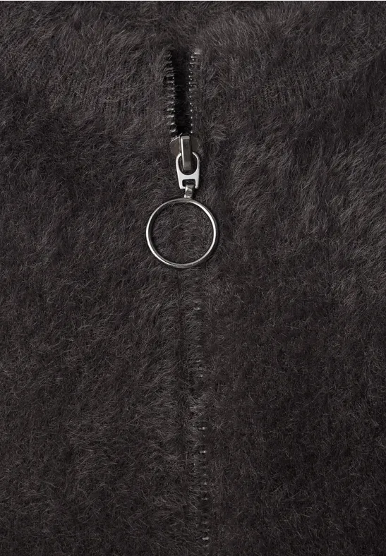 Flauschiger, schwarzer Stoff mit einem Reißverschluss und rundem Zipper-Anhänger.