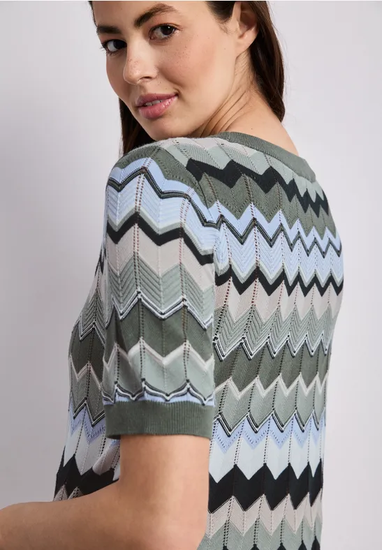 Persoon van achteren in een meerkleurig zigzagshirt met korte mouwen.