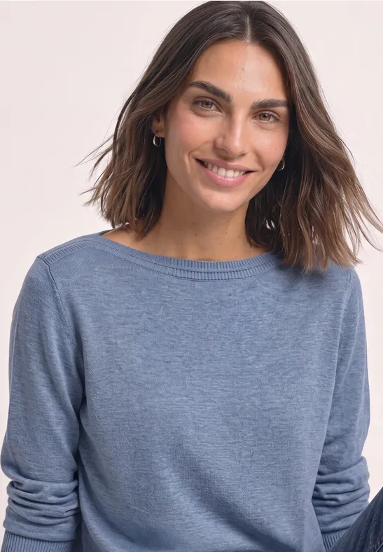 Portrait einer lächelnden Frau mit dunkelblonden Haaren und blauem Pullover