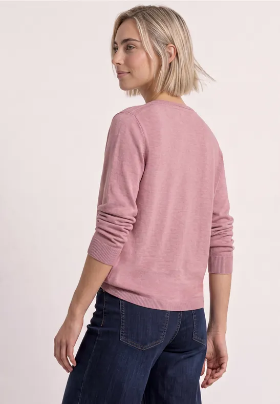 Junge Frau von hinten in rosa Pullover und blauer Jeans, schaut seitlich.