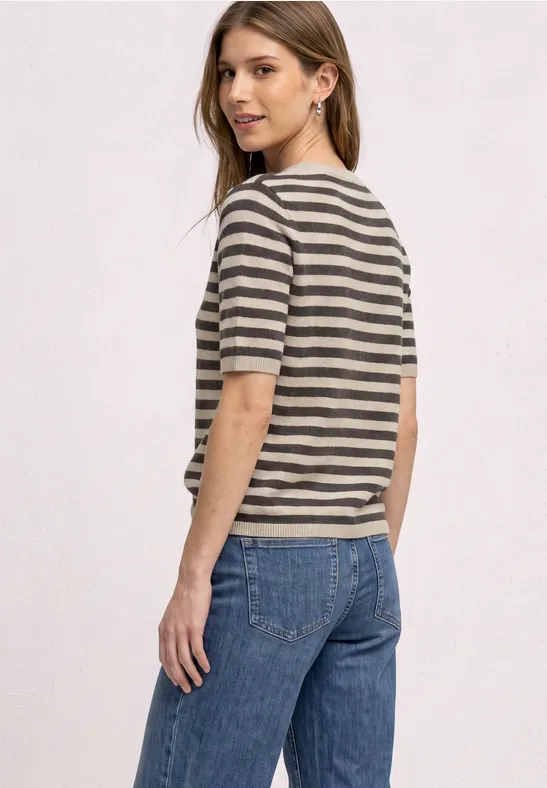 Frau in gestreiftem T-Shirt und Jeans, schaut über die Schulter.