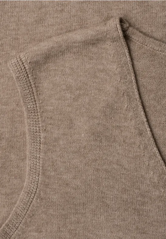 Nahaufnahme eines braunen Sweatshirt-Stoffes mit sichtbarem Taschenrand.