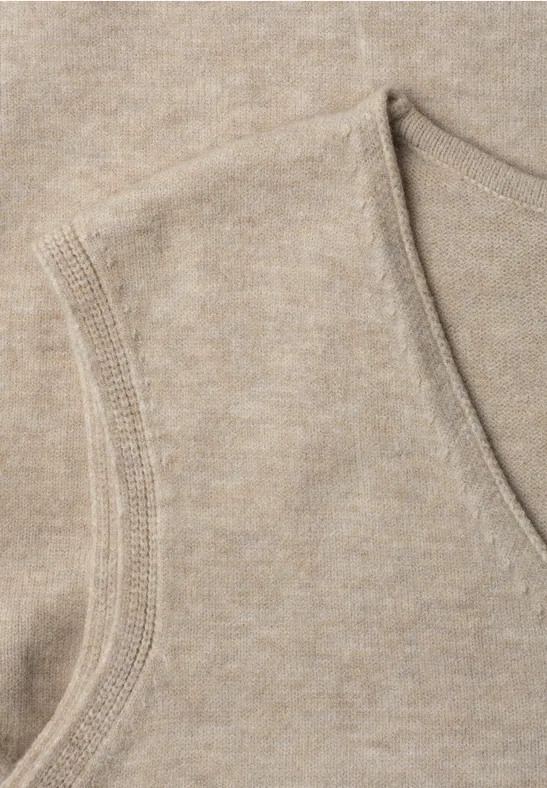 Nahaufnahme eines beige gestrickten, ärmellosen V-Ausschnitt-Oberteils.