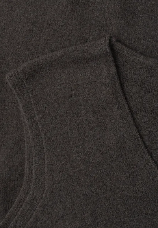 Nahaufnahme eines dunklen Kleidungsstücks aus Strickstoff mit sichtbarer Naht und Tasche.