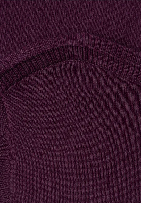 Nahaufnahme eines dunkelvioletten Strickstoffs mit geripptem Bund und sichtbarer Naht.
