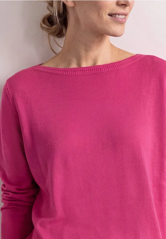 Frau mit pinkem Pullover, seitlich abgebildet vor neutralem Hintergrund.