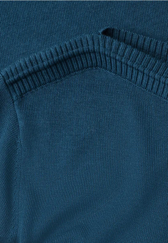 Nahaufnahme eines blau-grünen Strickpullovers mit Rippenstrickabschluss am Halsausschnitt.